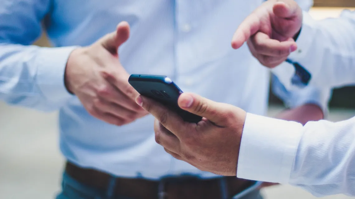 A person showing their phone to another person